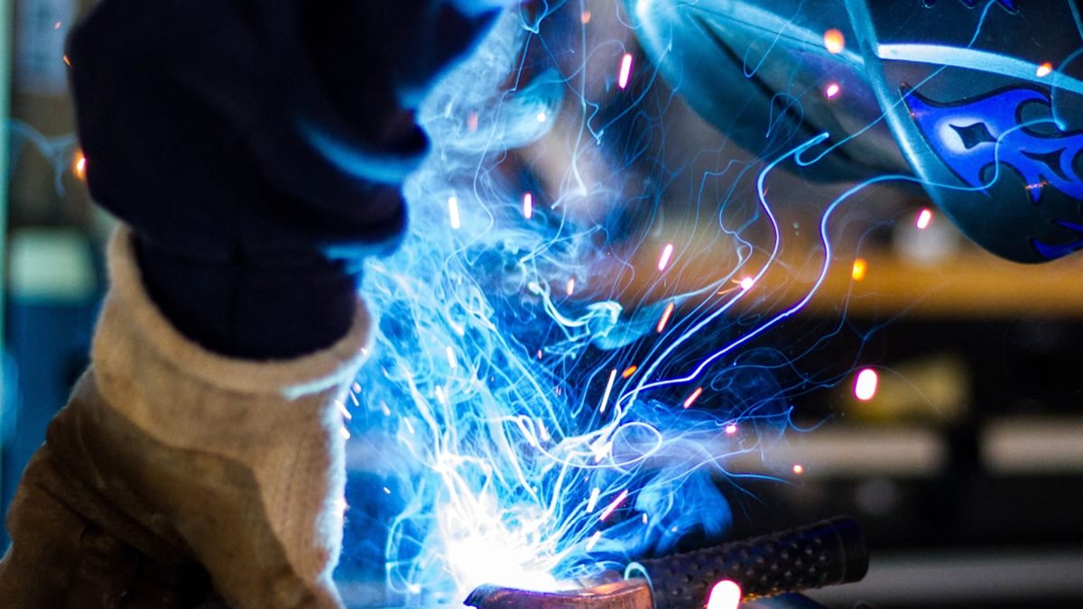 Close-up of a welder at work, with sparks flying from the weld