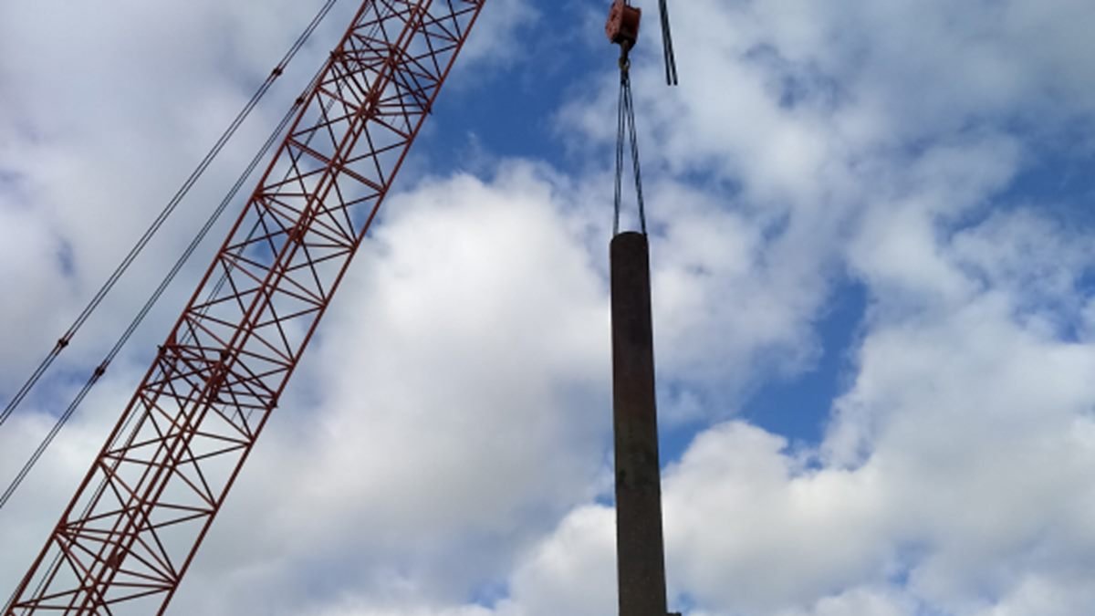 Crane lifting a long steel pile into position